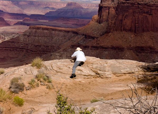 Photo by Don Ecsedy of Mary Ecsedy taking photographs from the rim of Island in the Sky overlooking the start of the Schafer Trail.